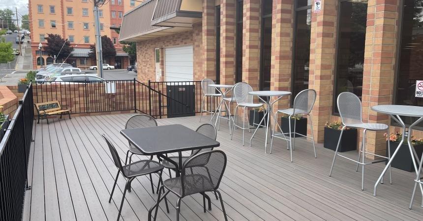 A photograph of the downtown library's outdoor reading area, with several metal chairs and tables.