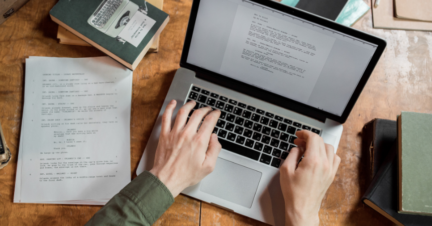 A pair of hands type on a laptop, writing a manuscript.