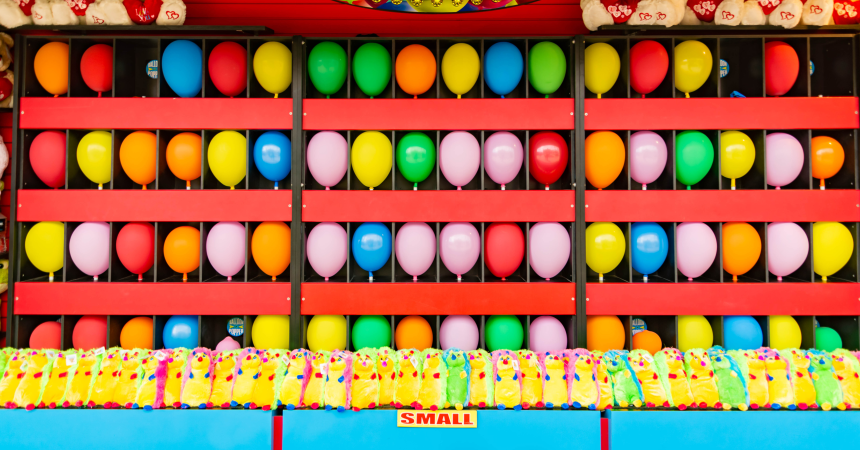 Rows of colorful balloons are set up in a dart-throwing carnival game.