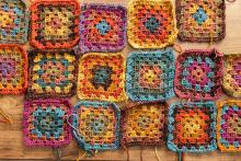 A selection of "granny square" crochet pieces in a rainbow of yarn colors.