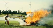 In the opening scene from Peacock, two people frantically spray a golf cart that's engulfed in flames with fire extinguishers.
