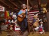 Red Yarn (Andy Furgeson) holds an acoustic guitar, surrounded by puppets and miscellaneous objects